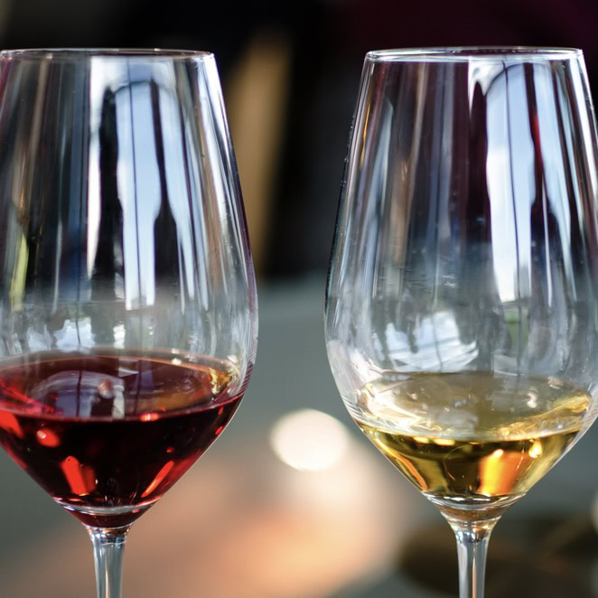 Two wine glasses, one with red wine and one with white wine, on a table at Strewn Winery.