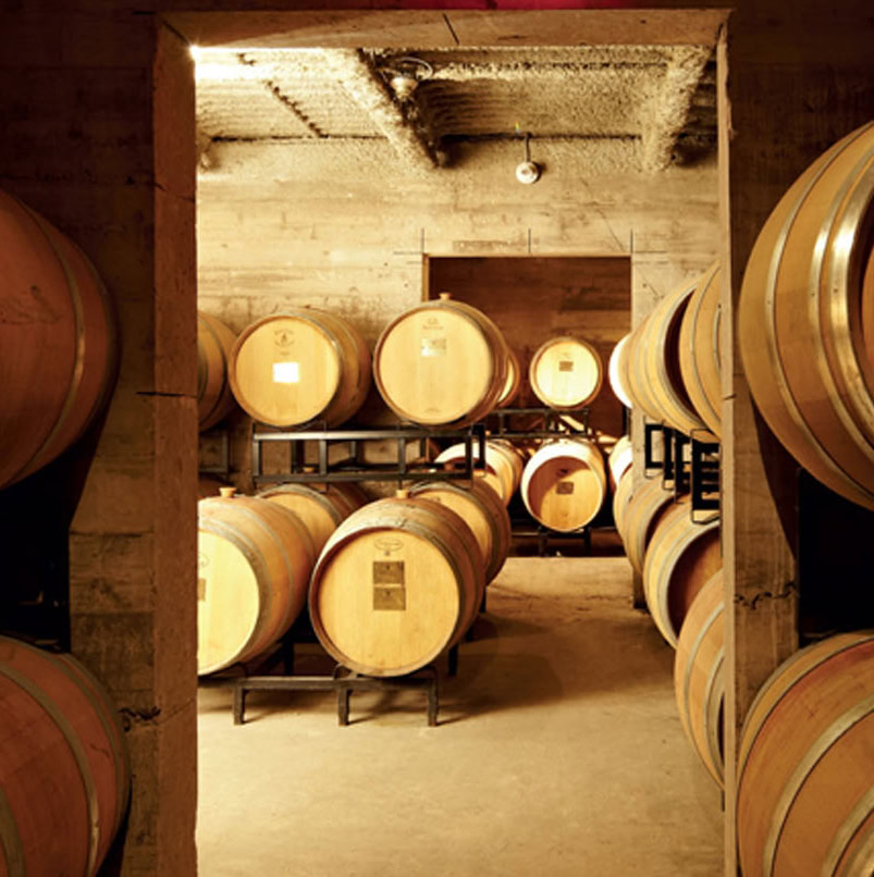 Wooden wine barrels stored in a cellar at Strewn Winery for aging wine.