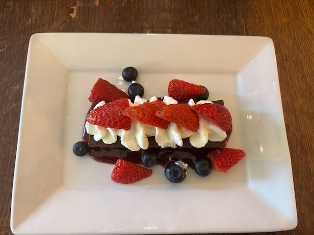 Dessert with strawberries, blueberries, whipped cream, and chocolate on a white plate at Strewn Winery.