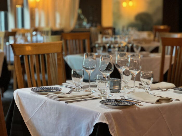 Close up of elegant table at restaurant with white tablecloth and place setting