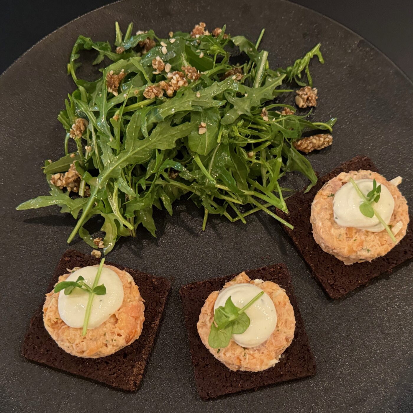 Gourmet appetizer with arugula salad and salmon tartare on dark plate at Strewn Winery.