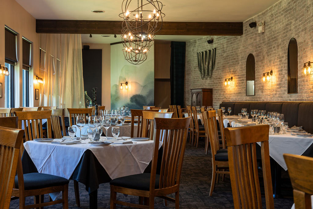 Interior of Terroir Restaurant with wooden chairs, white tablecloths, and ambient lighting.